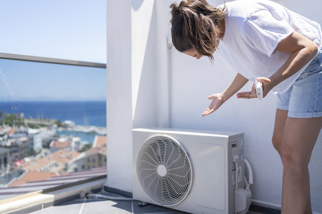 Woman Suffering From Heat And Checking The Broken Air Conditioner Outdoor Unit | Emergency Heating and AC Repair Service