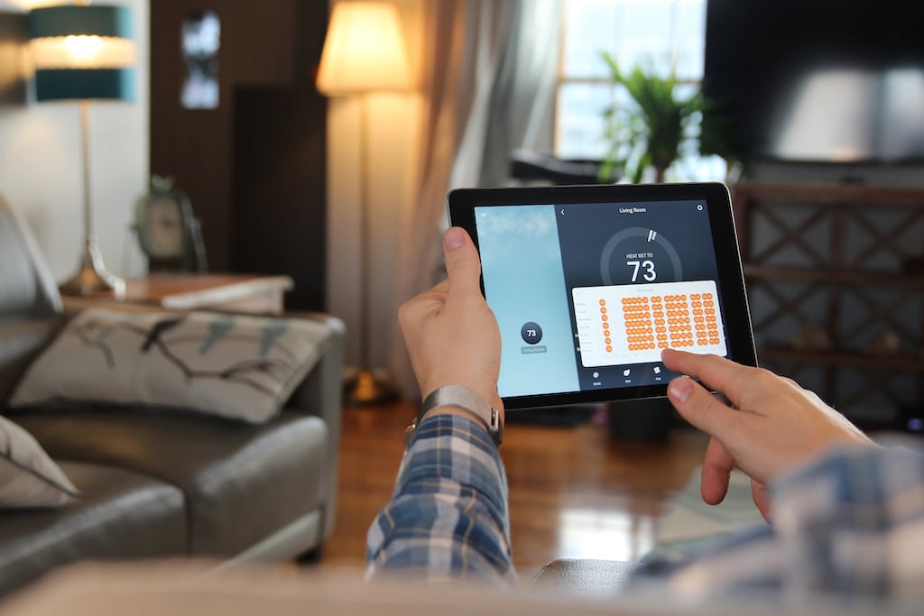Man adjusting his home temperature with a tablet. Easy with a reliable heating and AC repair company. 