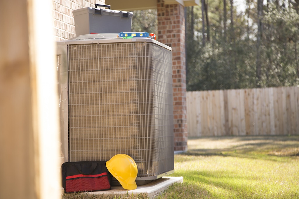 AC unit outside residential home with tools nearby for air conditioning service.