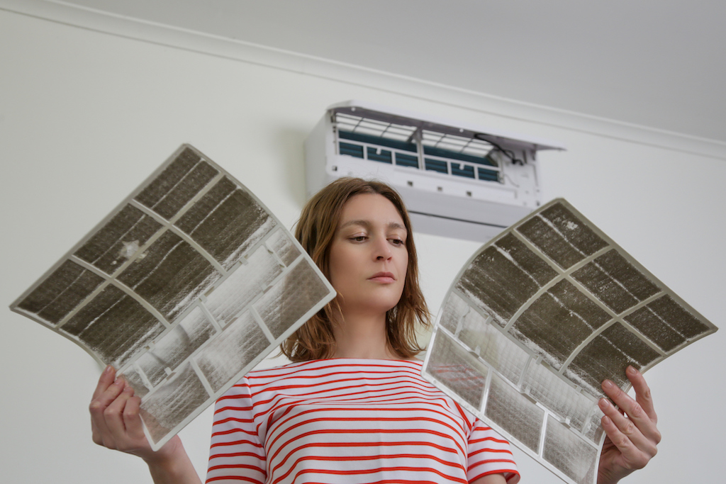 Woman holding two dirty ac filters in need of ac repair.