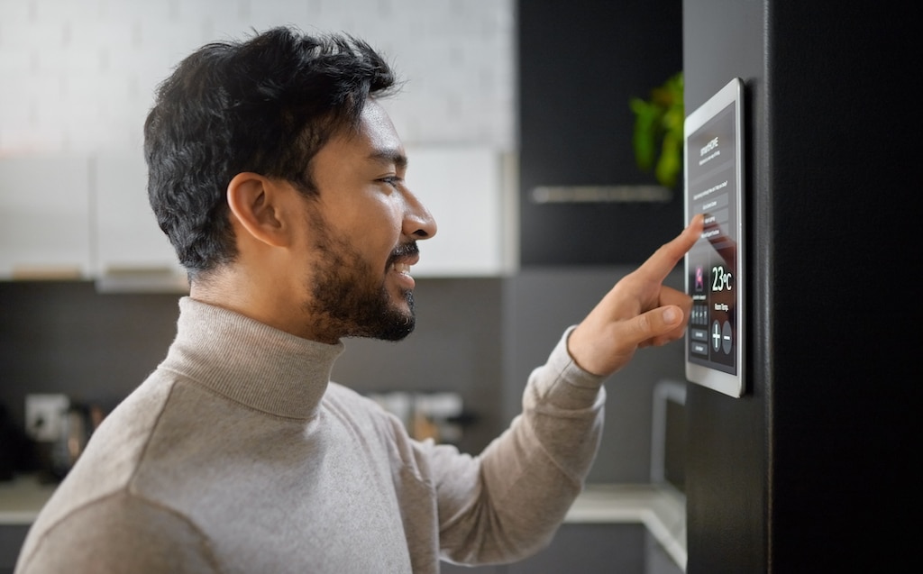 Man adjusting smart home thermostat in his apartment. Multi-Family Heating Systems