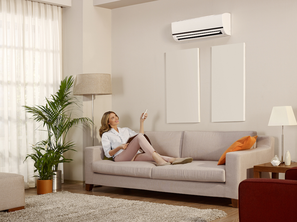 Woman relaxing on couch enjoying AC unit. | components of hvac system residential