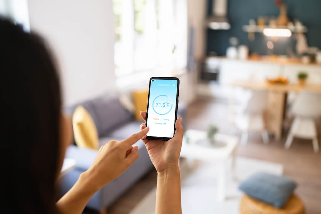 Woman adjusting her air conditioner from phone using smart technology. | Residential HVAC Design Guide
