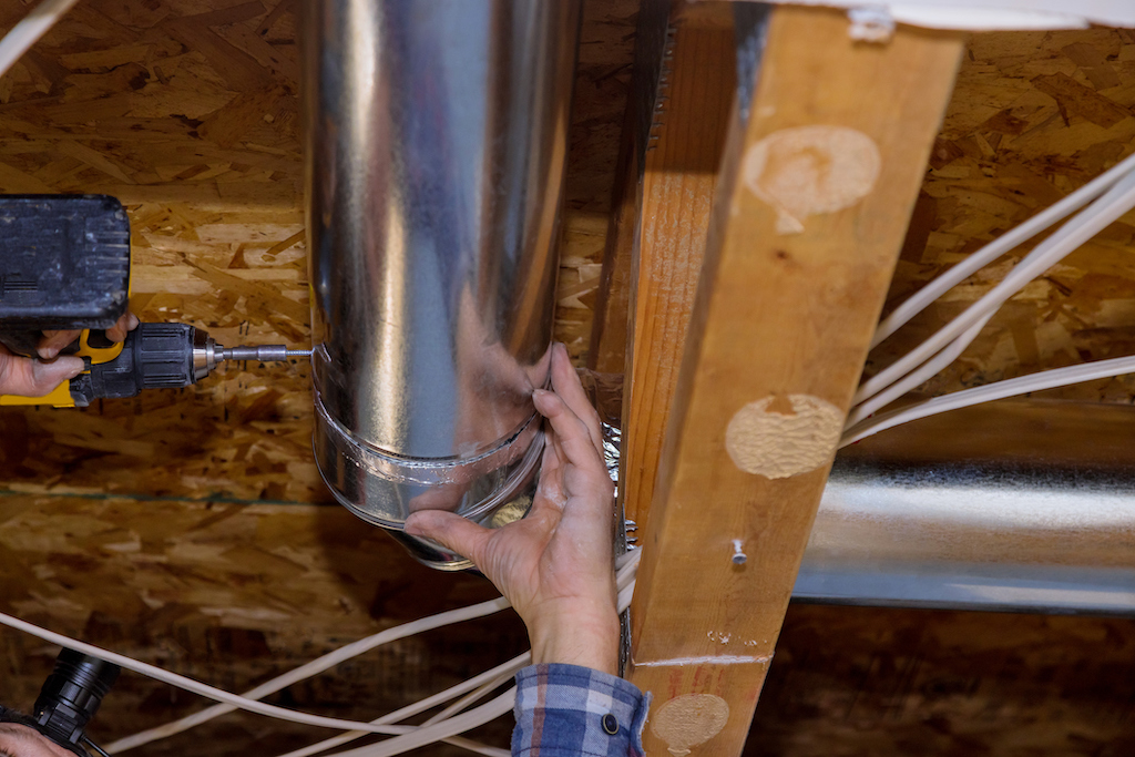 Technician installing ductwork in home attic. | Ducted AC Installation