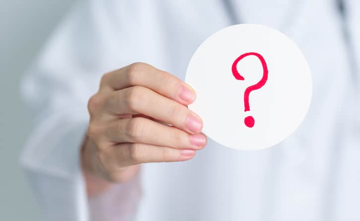 Woman holding up circle paper with red question mark. | AC Repair in Watauga