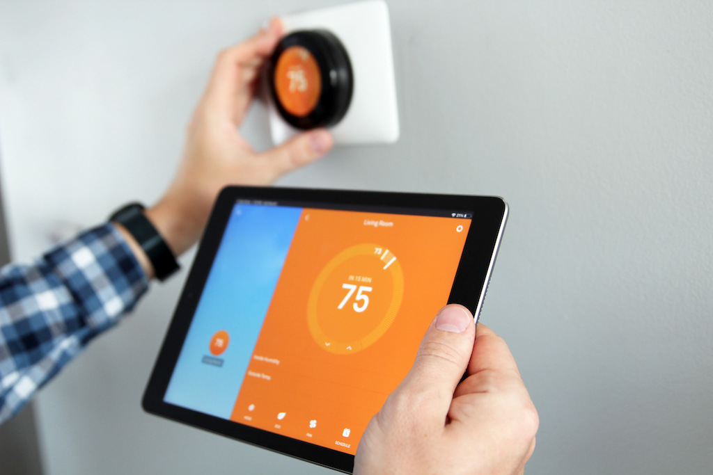Man controlling his temperature with an iPad and smart thermostat. | Residential HVAC System Components 