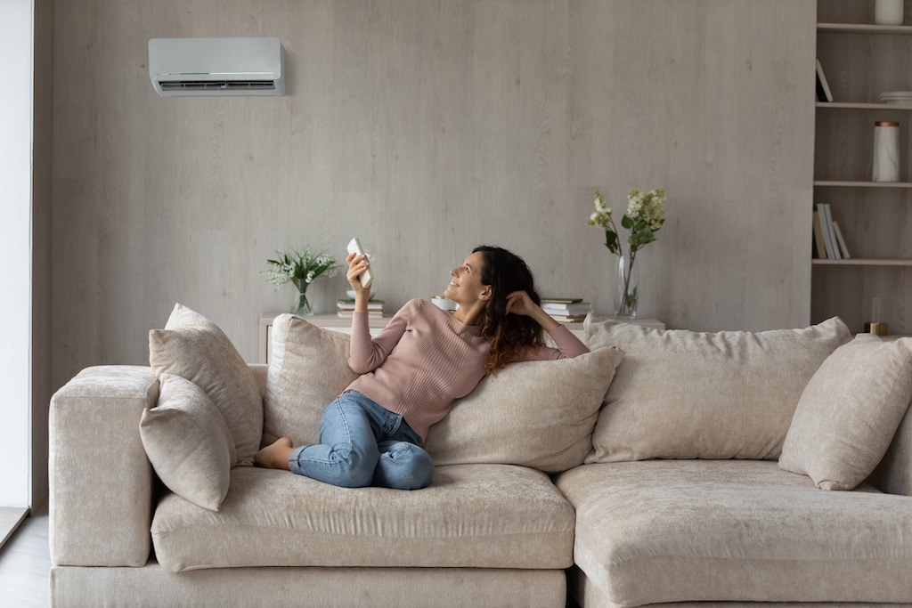 Woman relaxing on couch, turning down AC in home. | Air Mixing Box HVAC