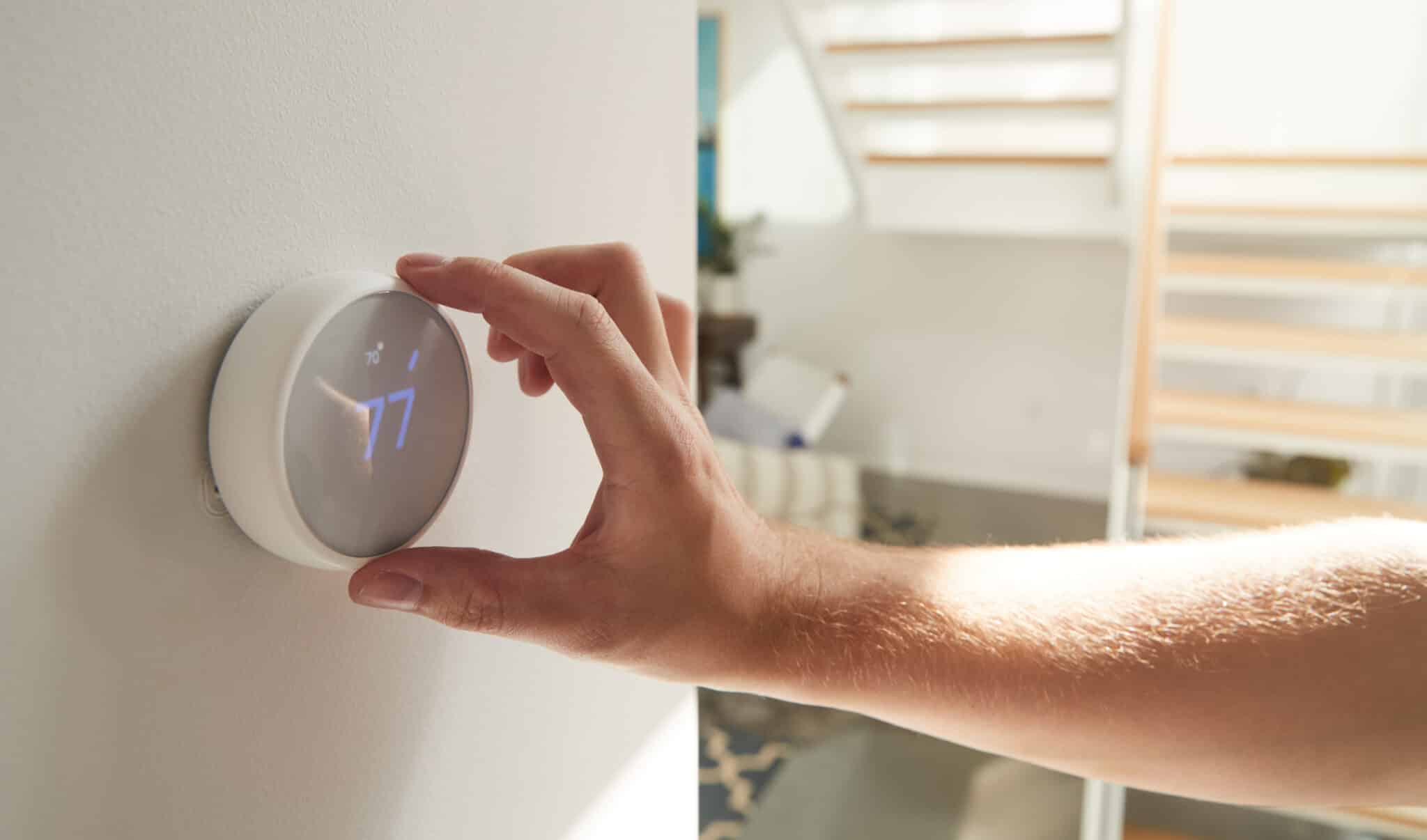 Close Up Of Male Hand Adjusting Digital Central Heating Thermostat In Home, HVAC.
