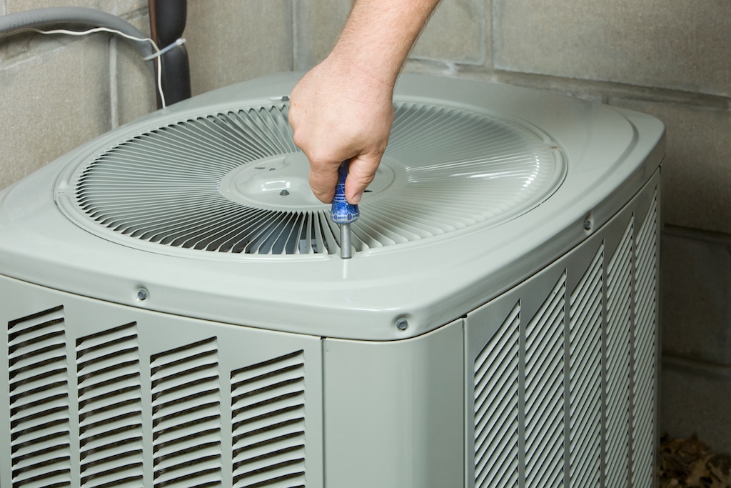 Service Technician Removing or Installing Air Conditioner Fan Cover. AC repair