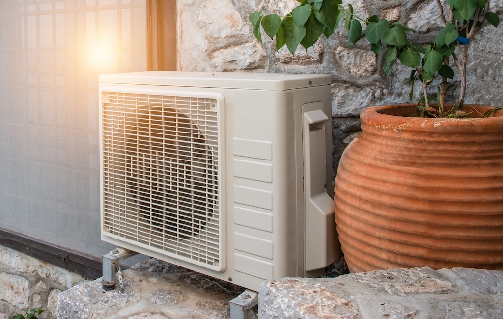 Close-up of air heat pump, air conditioning outdoor unit near window and wall of Greek house. Full inverter. AC installation