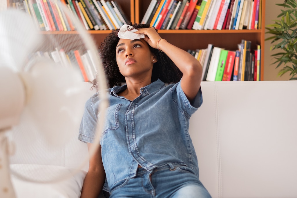 Woman sweating and trying to refresh at home. AC Installation