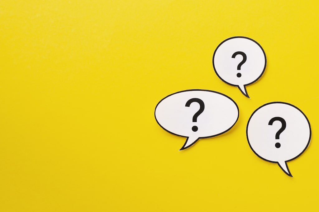 Yellow background with white speech bubbles with question marks. Representing FAQs about air conditioning.