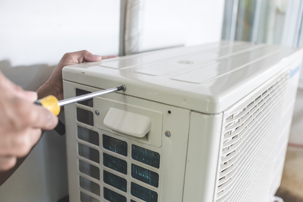 Technician opening top of ac unit with screwdriver. | Air Conditioning Service