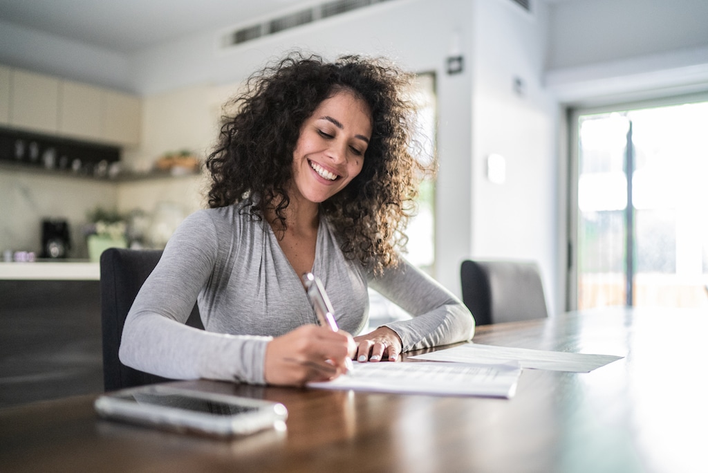 A woman sitting at her dining table making an AC Installation Checklist.