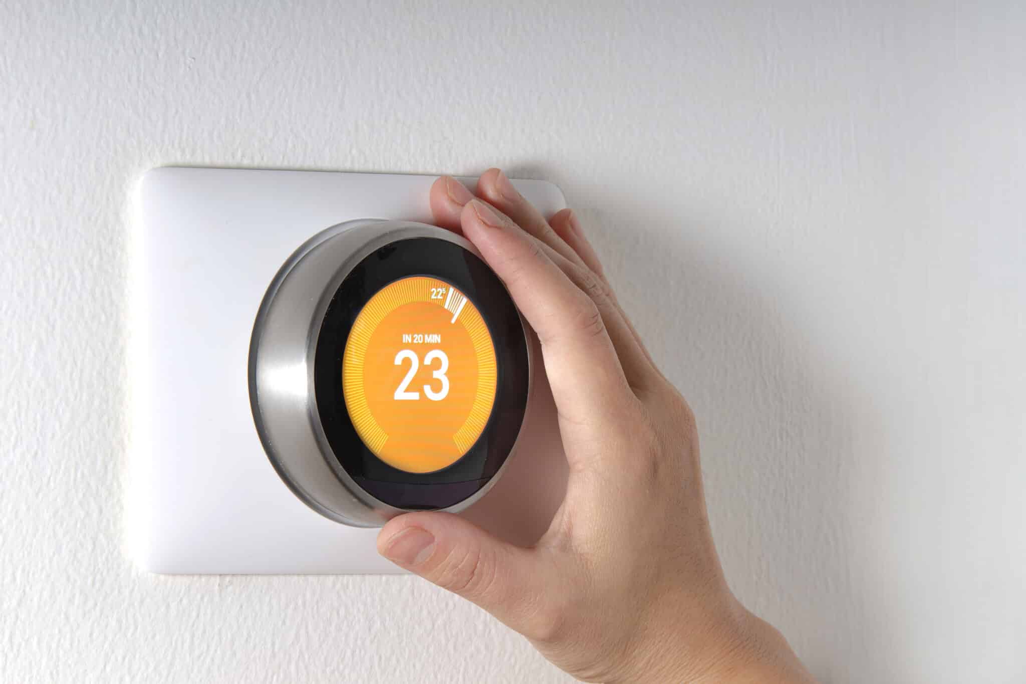 Smart Thermostat with a hand setting up the temperature, HVAC Efficiency.