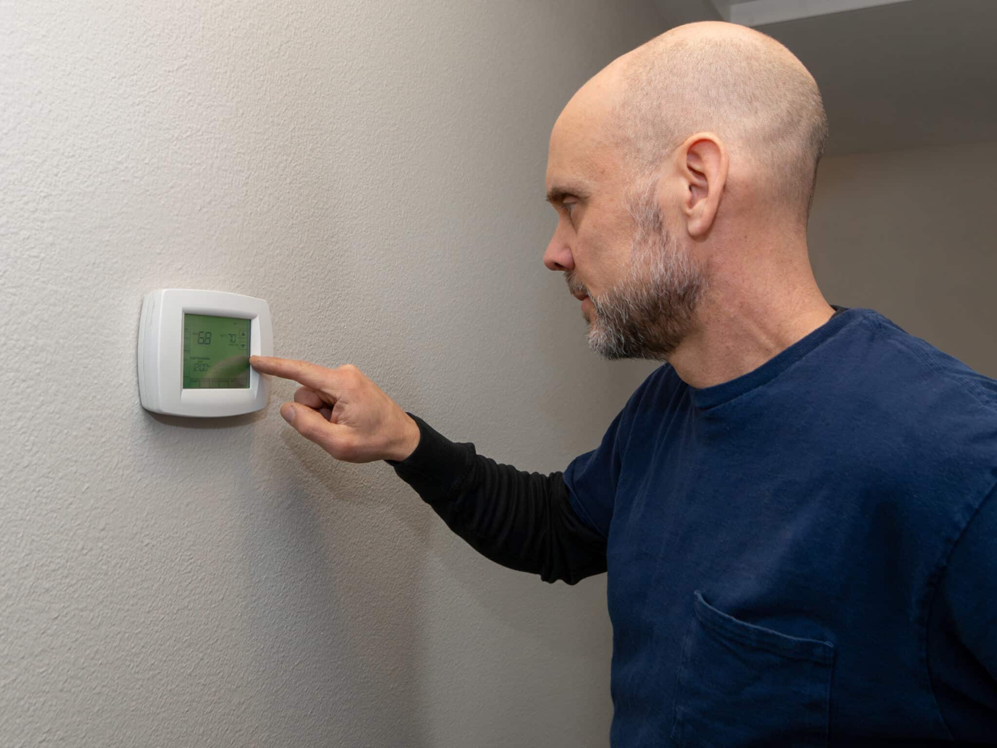 Home inspector examining a home thermostat near living room, Smart Control Systems.