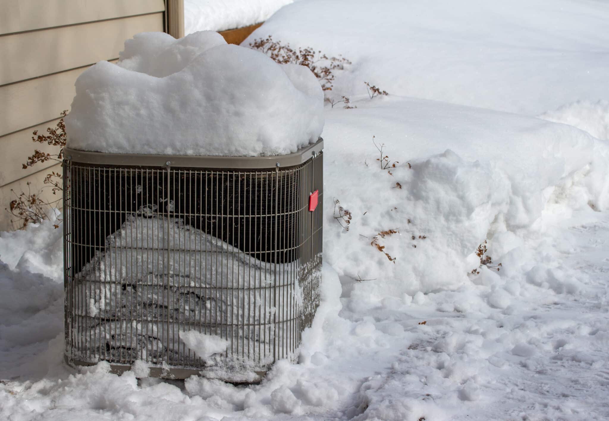 The exterior air conditioner unit is covered with deep snow, causing the AC not to turn on.