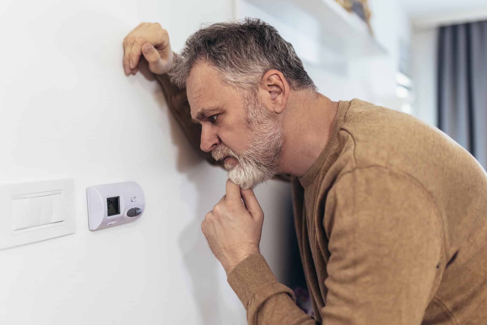 A Man Adjusting Thermostat Settings That May Not Be Optimized.