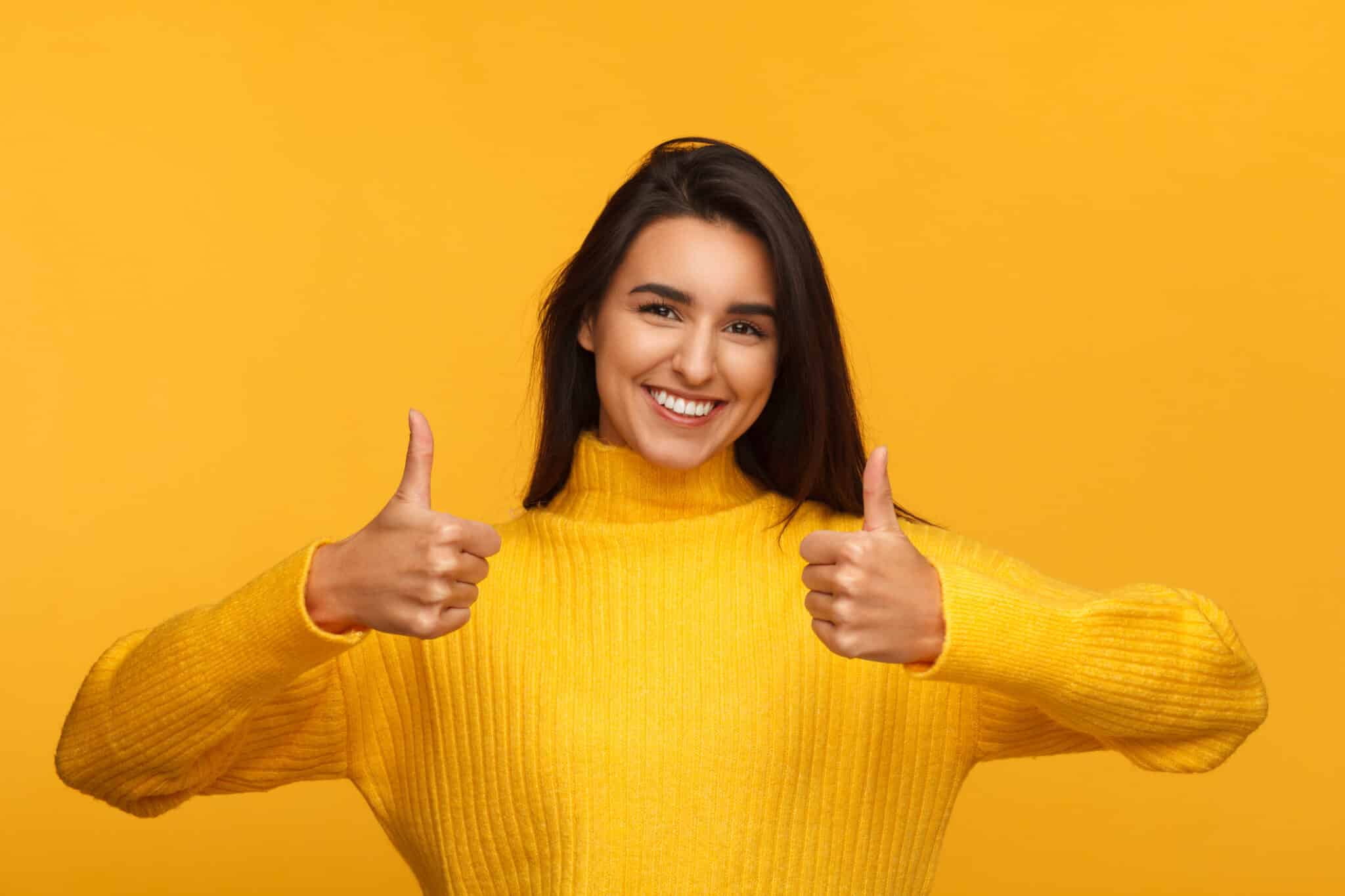 A woman on a yellow background gives a thumbs-up for choosing the right HVAC contractor and air handler.
