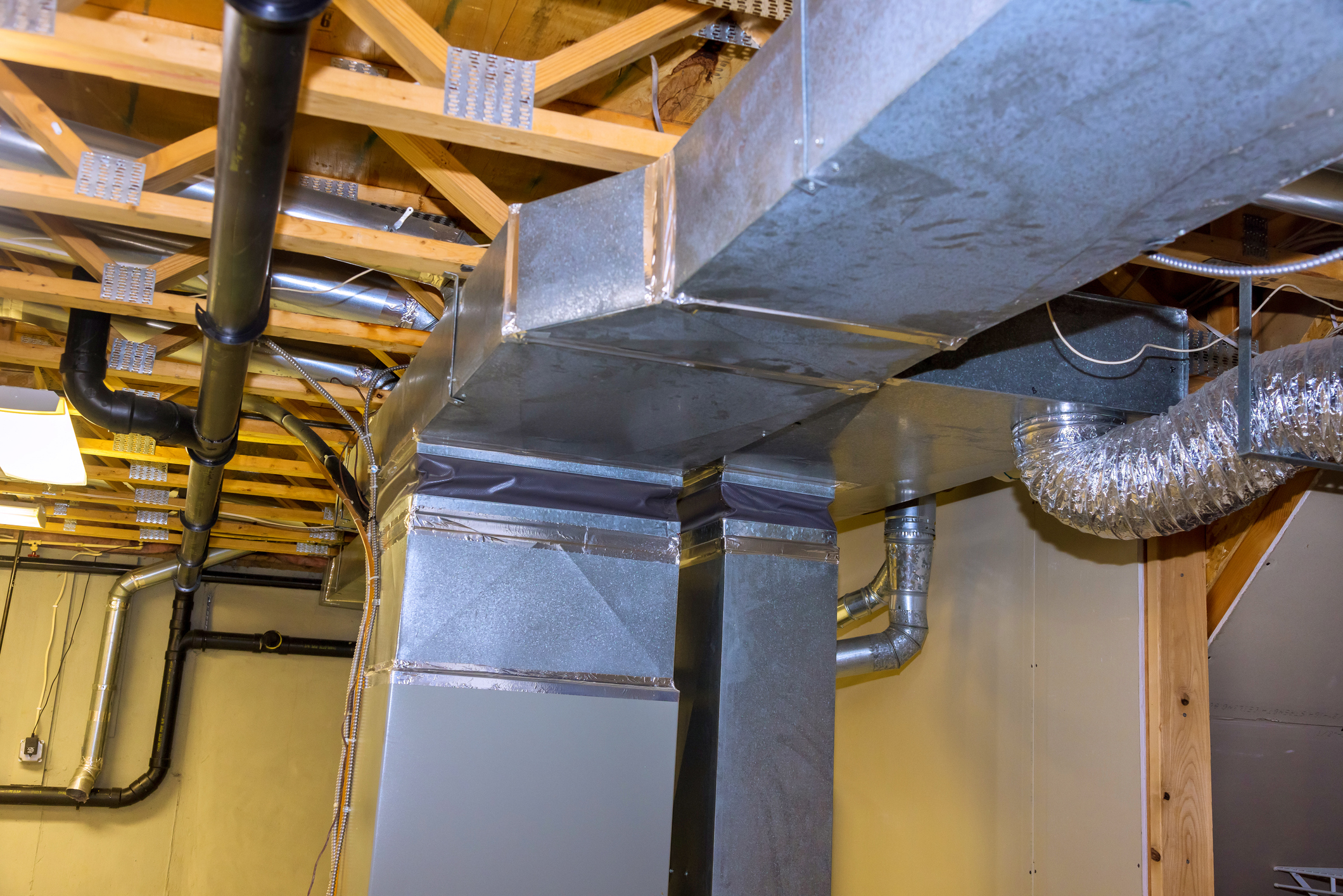 Residential basement metal ductwork requiring duct insulation repair to prevent condensation.
