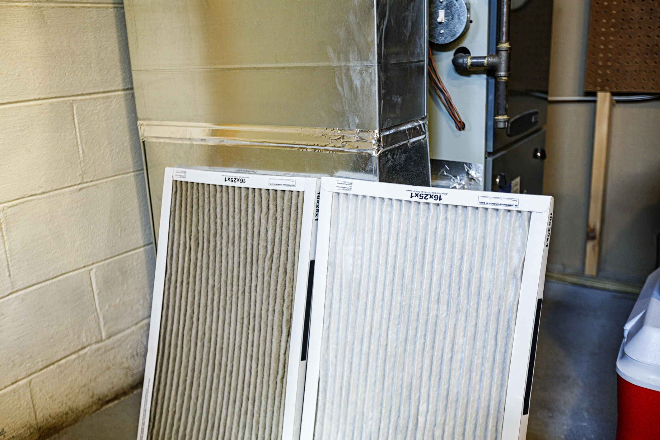 Clean and dirty residential HVAC air filters with a filter change schedule guide.